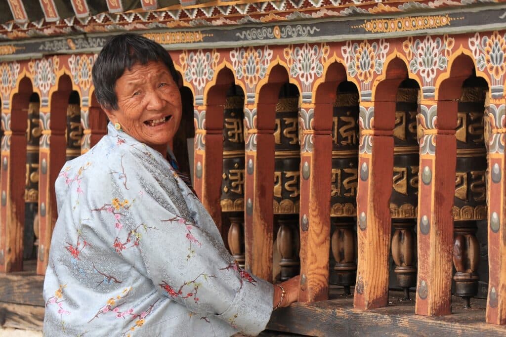 Viaggiare in Bhutan: anziana fa girare la ruota del dharma. Ruota della preghiera Buddista